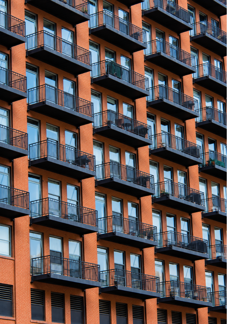 Orange brick apartment building with rows of black metal balconies